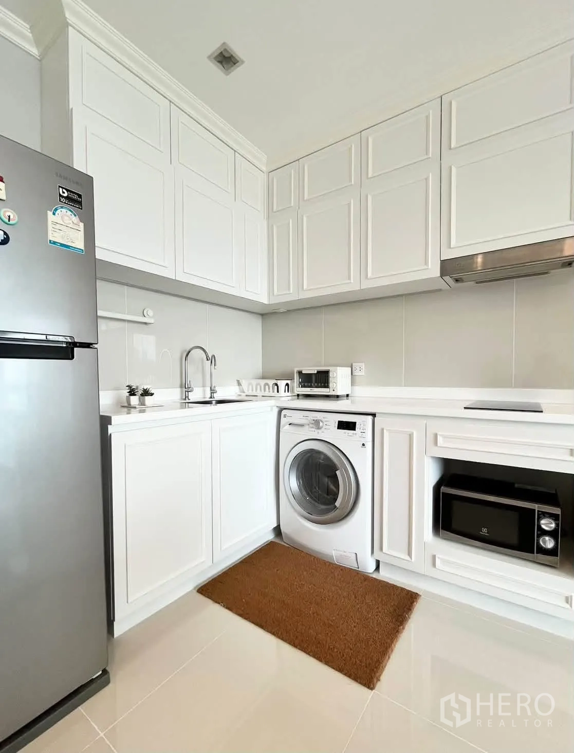 Condominium for rent in Pathum Wan, Bangkok - White built-in kitchen with fridge, washing machine, microwave, and sink.