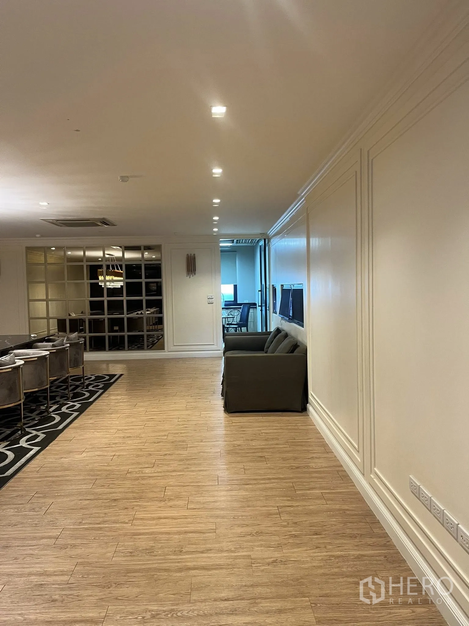 家庭办公室 for rent in Watthana, Bangkok - 宽敞走廊休息区，木地板、沙发与嵌灯照明。