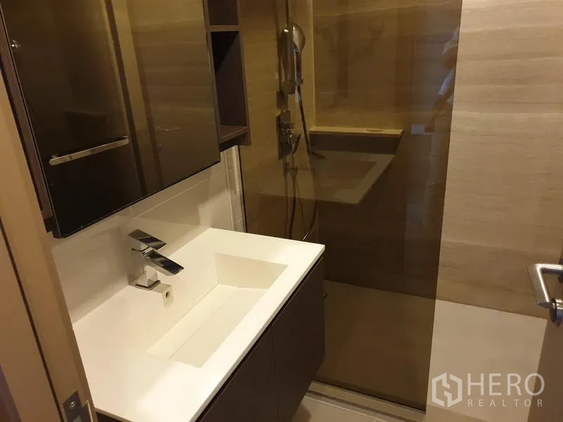 公寓 出租在Watthana, Bangkok - 现代卫浴，宽台面洗手盆、镜柜与玻璃淋浴间。
