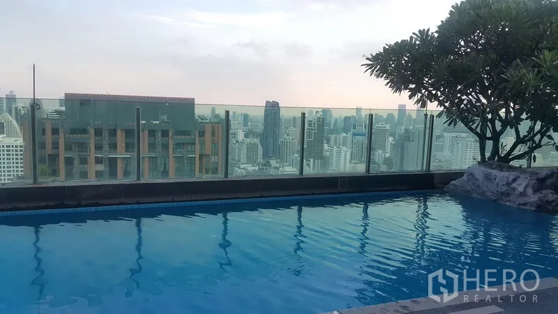 公寓 出租在Ratchathewi, Bangkok - 屋顶泳池，玻璃护栏，俯瞰曼谷城市天际线。