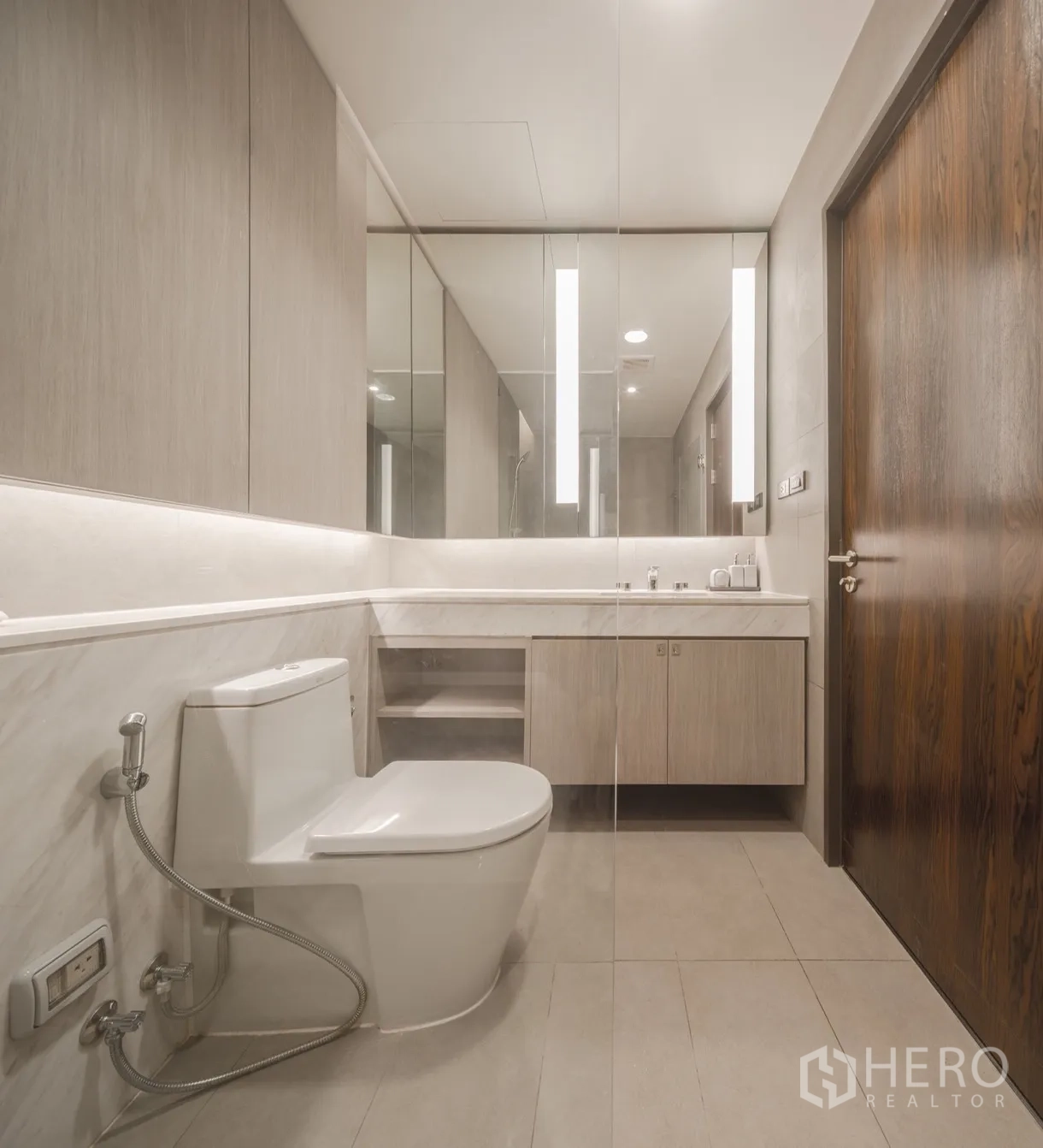 Condominium for rent in Khlong Toei, Bangkok - Bathroom with soaking tub and handheld shower against light-tone tiles.