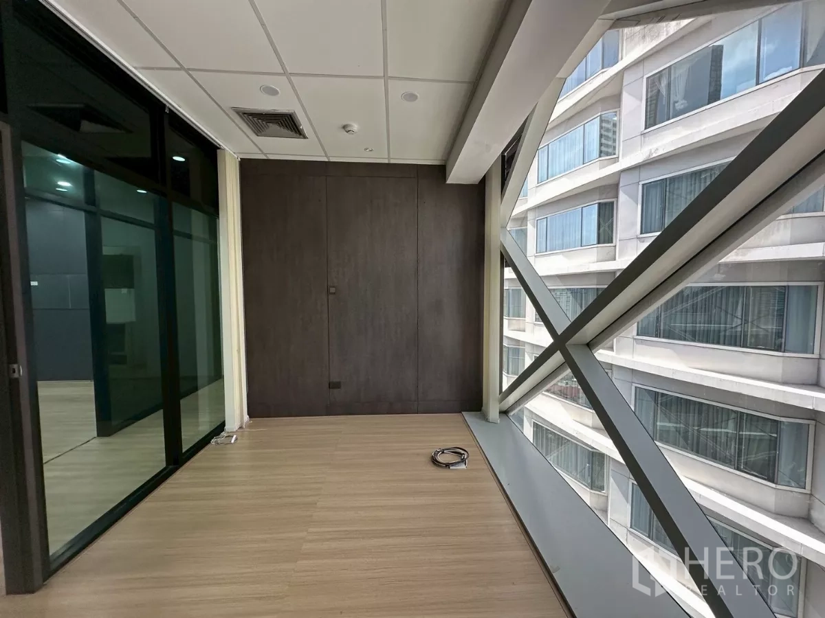 办公空间 出租在Watthana, Bangkok - 临窗阳光区，落地窗与交叉支撑，旁有玻璃隔断。