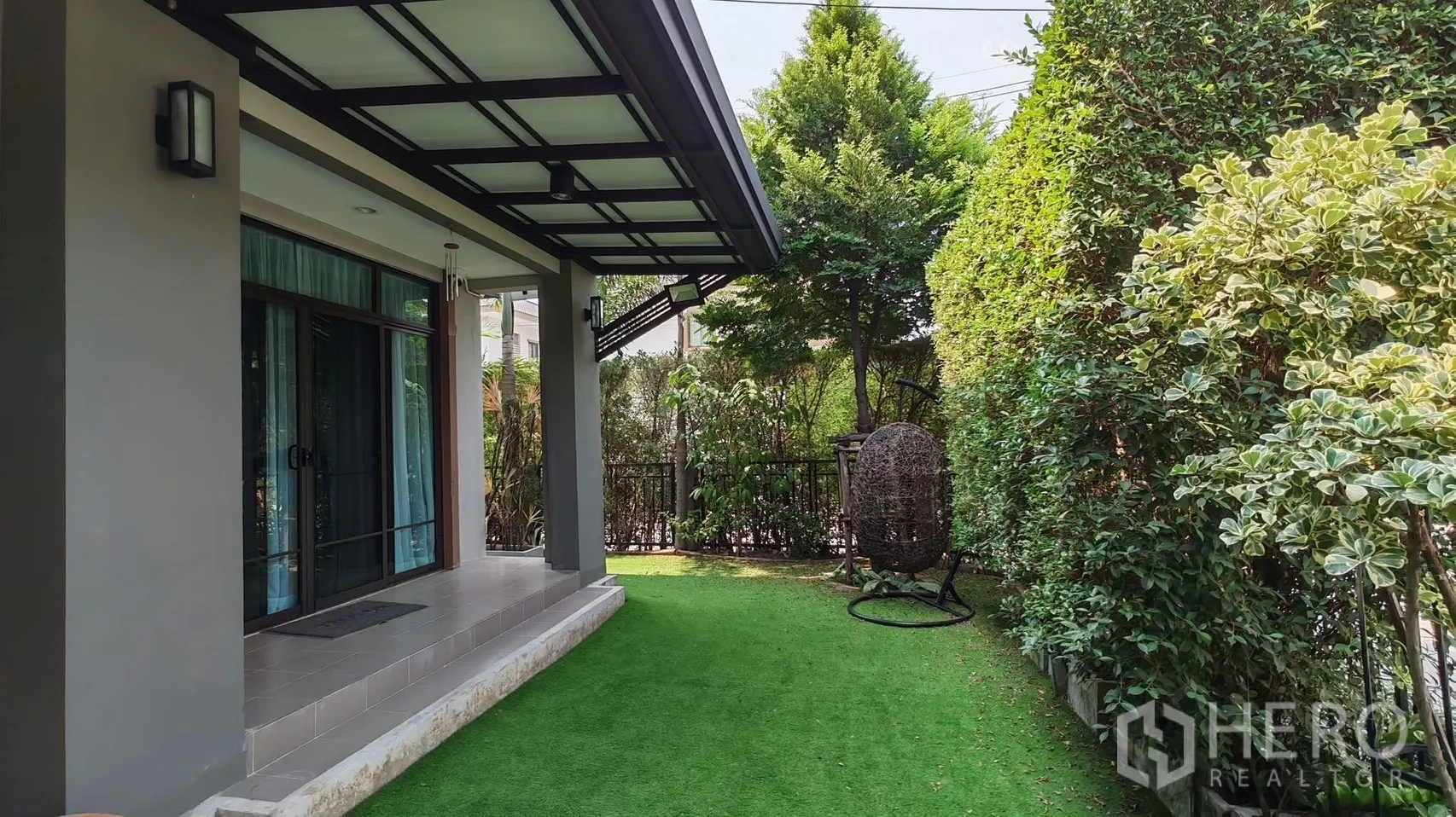 独栋房屋 for rent or sale in Bang Phli, Samut Prakan - 带顶前廊连接私家庭院草坪，周围是茂密树篱。