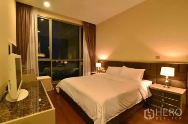 Condominium for rent in Watthana, Bangkok - Master bedroom with large window, upholstered headboard and bedside lamps.