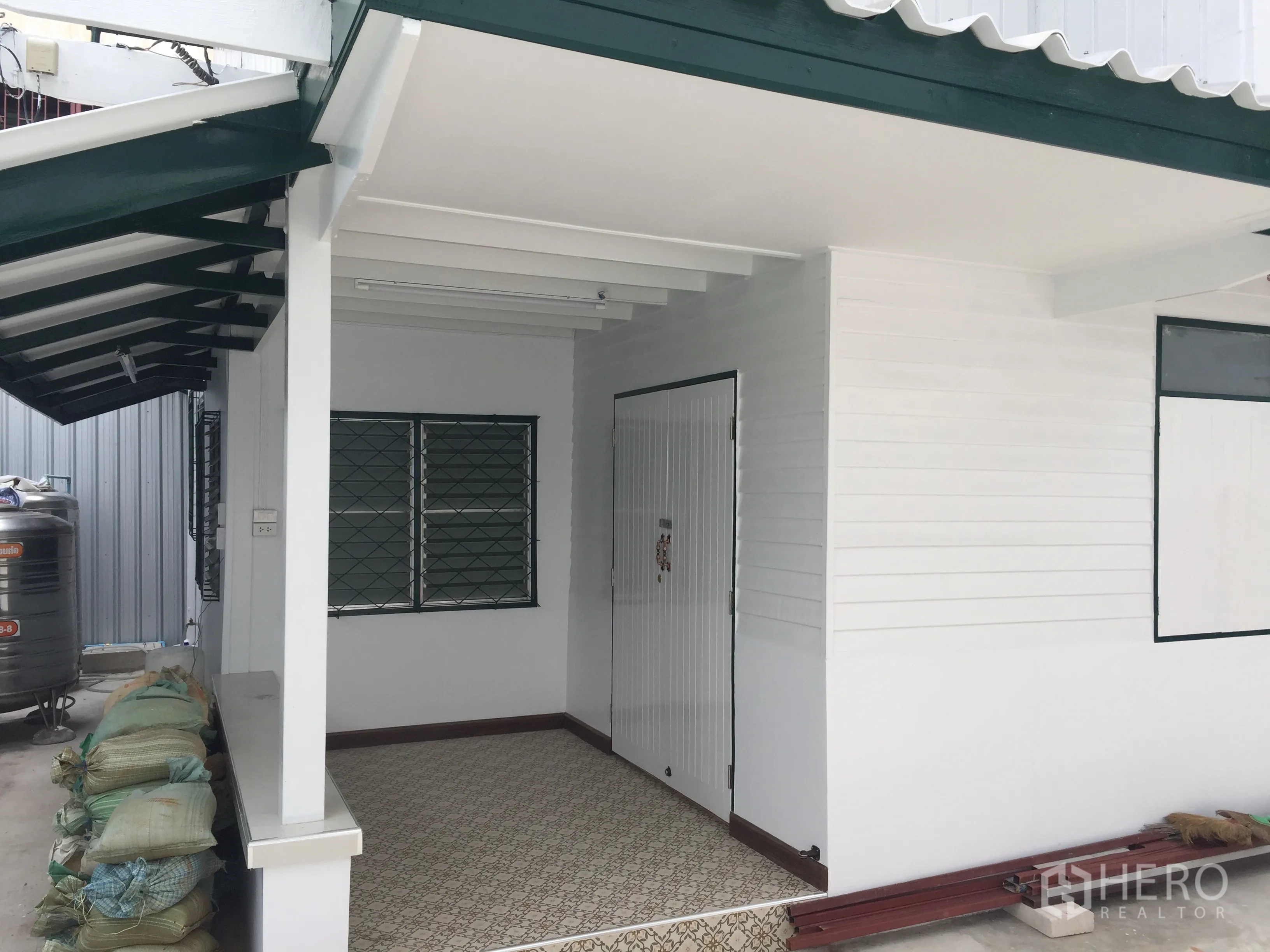 บ้าน ให้เช่าในBang Rak, Bangkok - หน้าบ้านทาสีใหม่ มีระเบียงหลังคา หน้าต่างเหล็กดัด และชายคาสีเขียว
