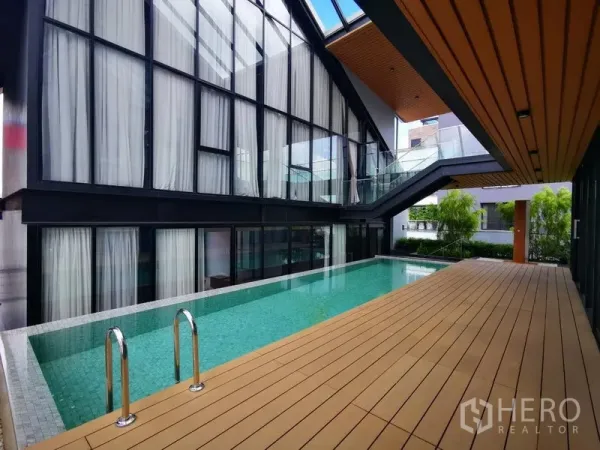 Apartment for rent in Khlong Toei, Bangkok - Modern lap pool with timber deck beside a glass-walled building and an elevated staircase.