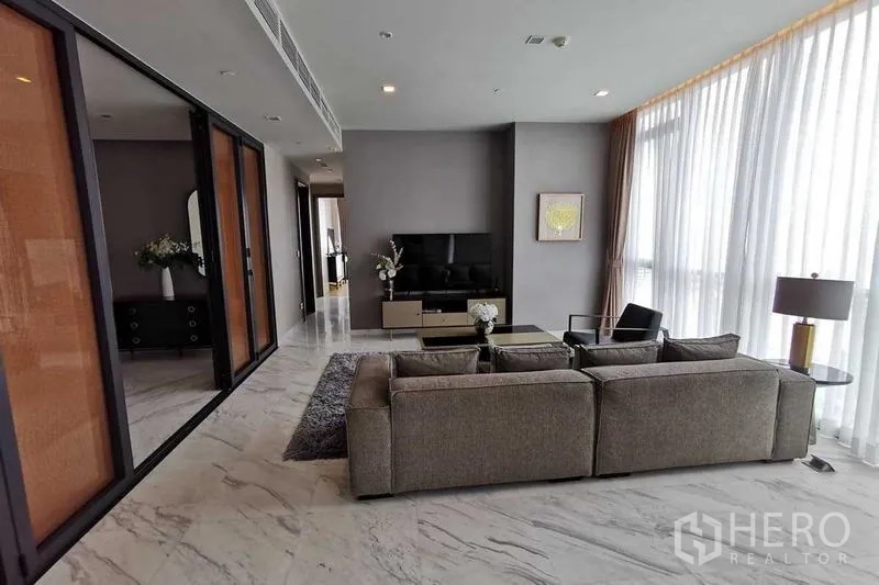 Condominium for rent or sale in Watthana, Bangkok - Living room viewed from behind the sofa, adjacent to wall-to-wall windows.