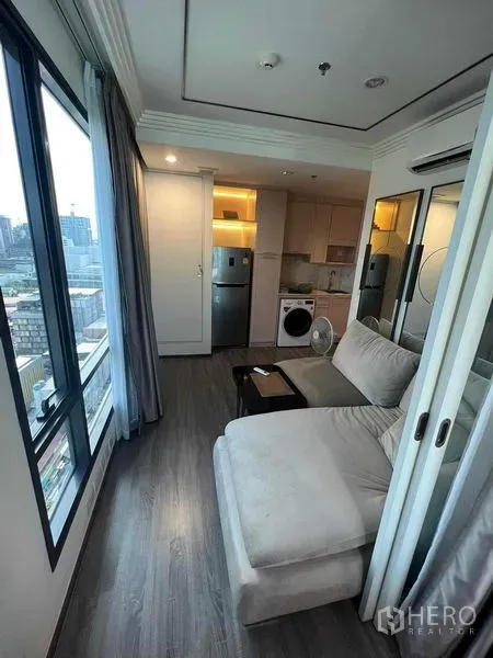 公寓 出售在Ratchathewi, Bangkok - 开放式起居区连接紧凑厨房，旁有冰箱与洗衣机，临落地窗。