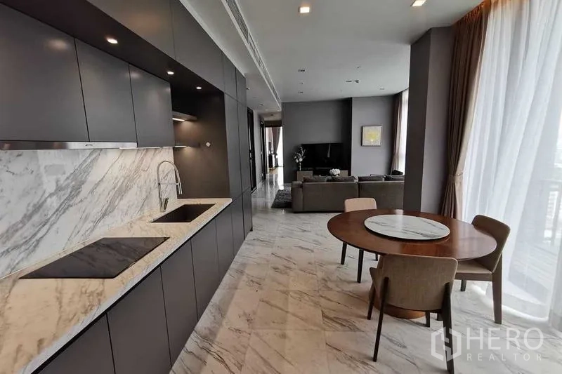 Condominium for rent or sale in Watthana, Bangkok - Open kitchen with marble backsplash, dark cabinetry and a round dining table.