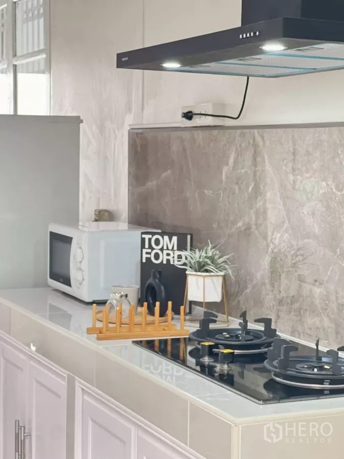 Detached House for rent in Huai Khwang, Bangkok - Kitchen counter close-up featuring gas hob, vent hood and small plants.