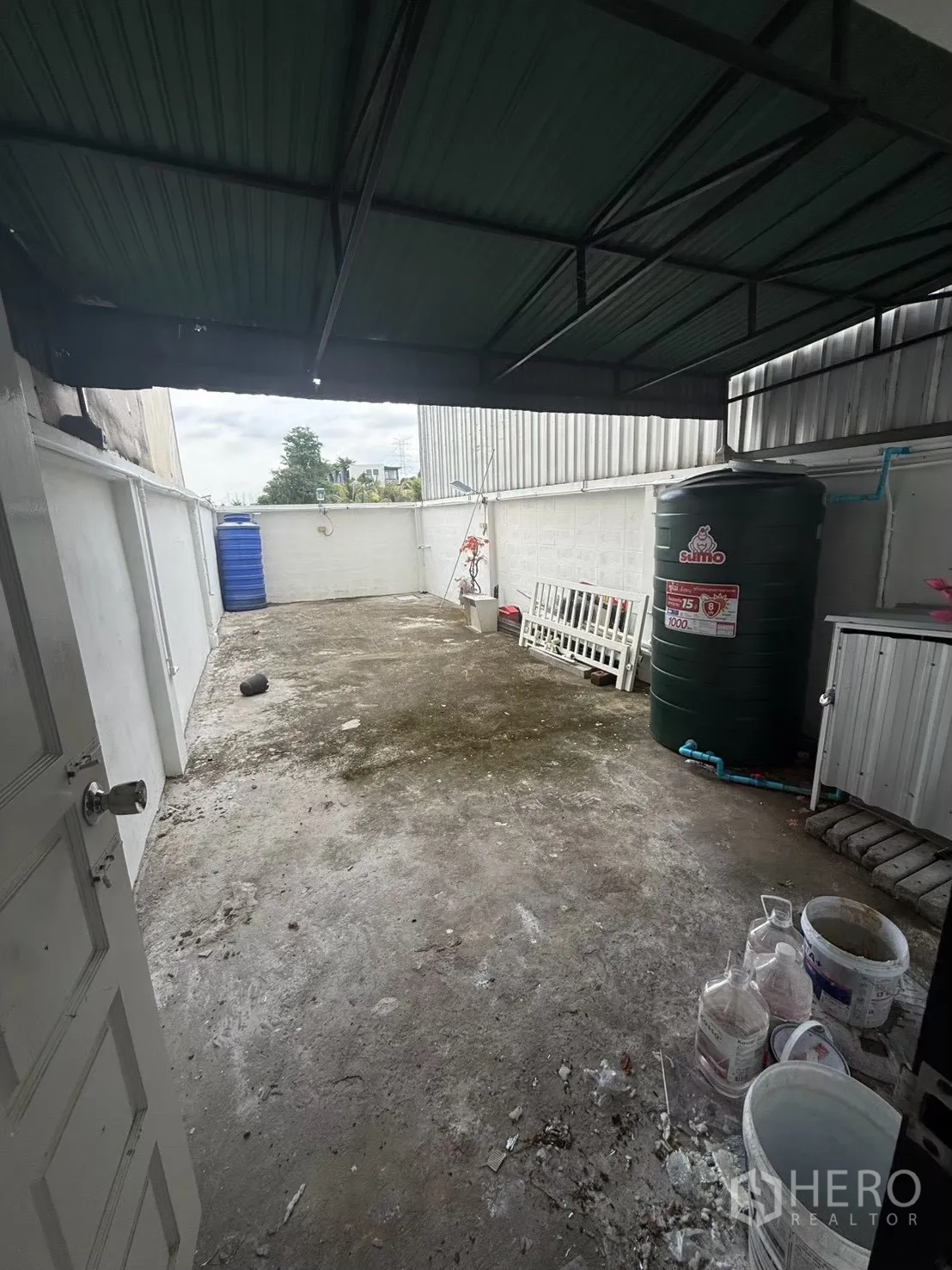 Shophouse for rent in Pak Kret, Nonthaburi - Open backyard space with storage tank under a metal awning.
