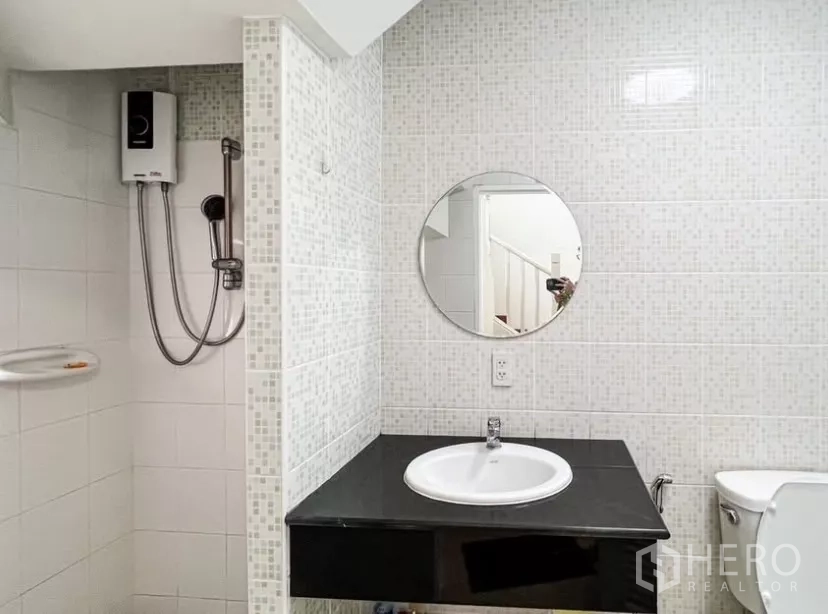 Detached House for rent or sale in Prawet, Bangkok - Bathroom with shower unit, round mirror and tiled walls.