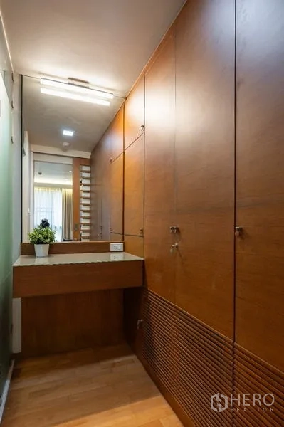 Condominium for sale - Walk-in wardrobe with full-height wooden cabinets and dressing table.