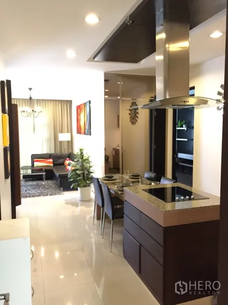Condominium for rent in Khlong Toei, Bangkok - Open-plan Bangkok condo with island kitchen, dining for four, and living area with sofa and rug.