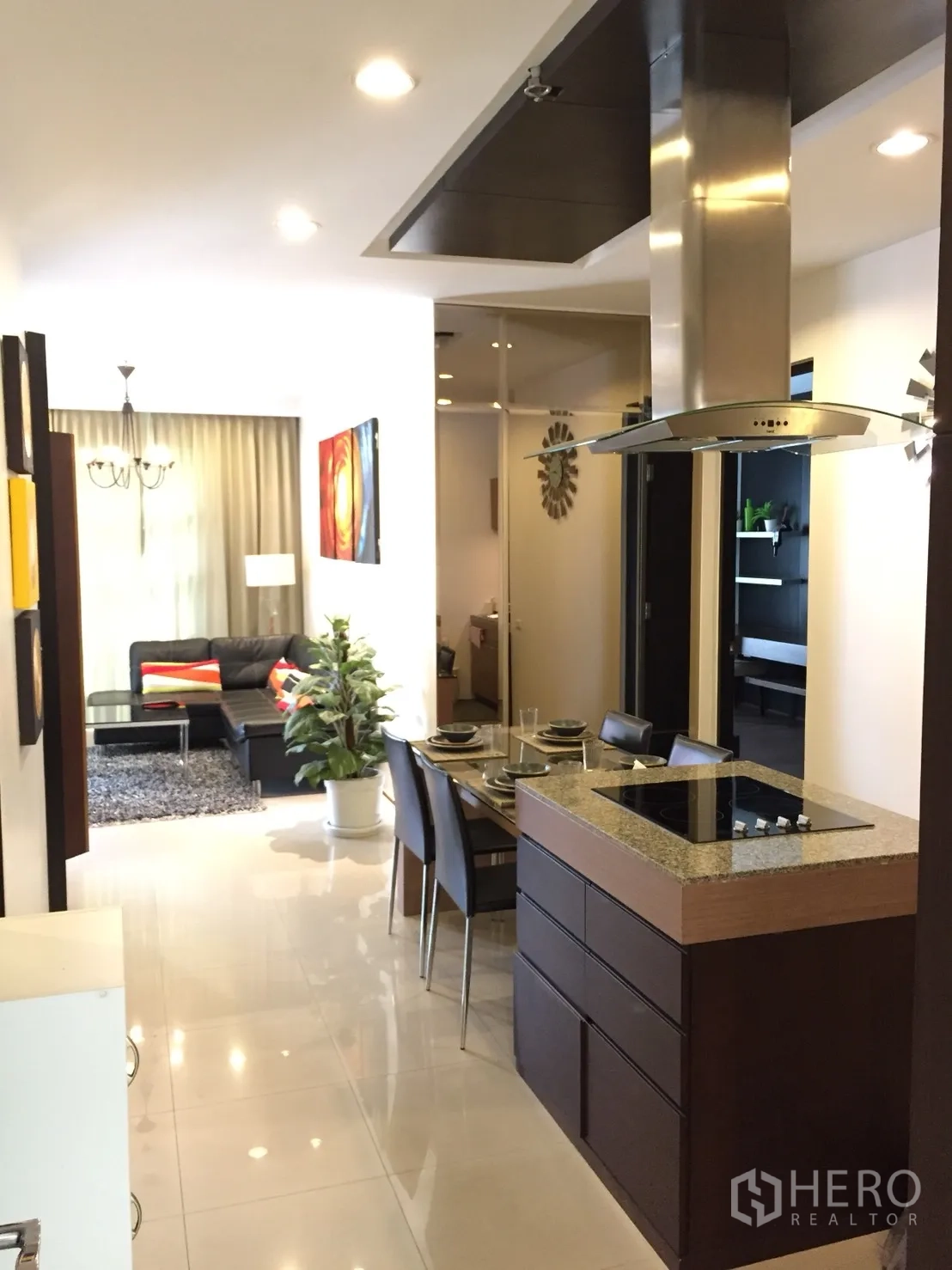 Condominium for rent in Khlong Toei, Bangkok - Open-plan Bangkok condo with island kitchen, dining for four, and living area with sofa and rug.