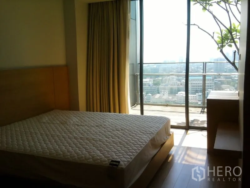 Condominium for rent in Sathon, Bangkok - Master bedroom with floor-to-ceiling window and balcony offering panoramic city views.