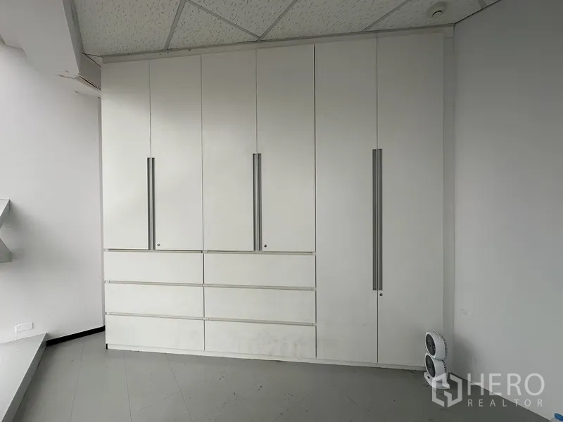 Office Space for rent in Watthana, Bangkok - Built-in white storage cabinets with tall handles inside the office.