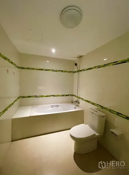 公寓 出租或出售在Watthana, Bangkok - 卫生间内置浴缸，配手持花洒与浅色装饰线条。
