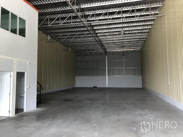 Factory for rent in Khlong Luang, Pathum Thani - Open production area with pendant lights, smooth floor and access to the office and restroom.