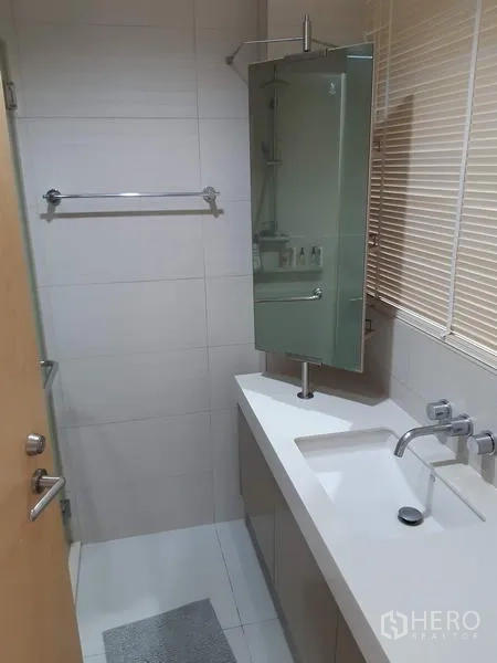 Condominium for rent in Khlong Toei, Bangkok - Clean bathroom with long vanity, wall-mounted faucet, mirror cabinet and tiled walls.
