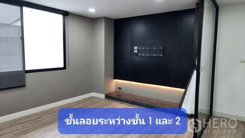 Townhouse for rent in Bueng Kum, Bangkok - Cozy living area featuring a black media accent wall with LED lighting and a large window.