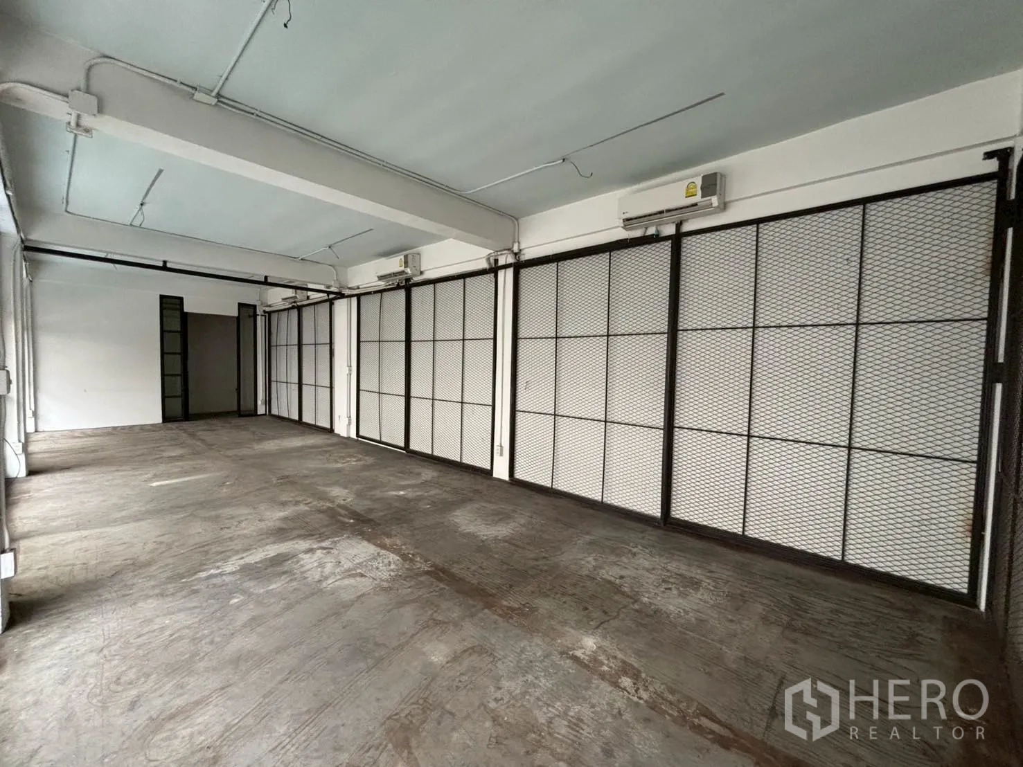 Retail Space for rent - Loft-style retail interior showing split-type air conditioners and sliding mesh panels along one wall.