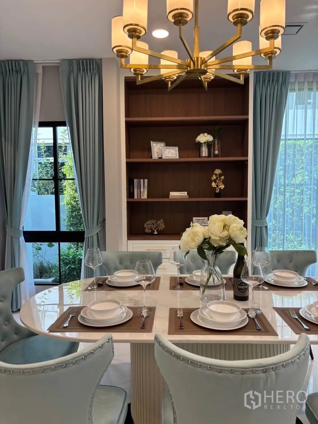 Detached House for rent in Saphan Sung, Bangkok - Elegant dining table under a gold chandelier with built-in shelving behind.
