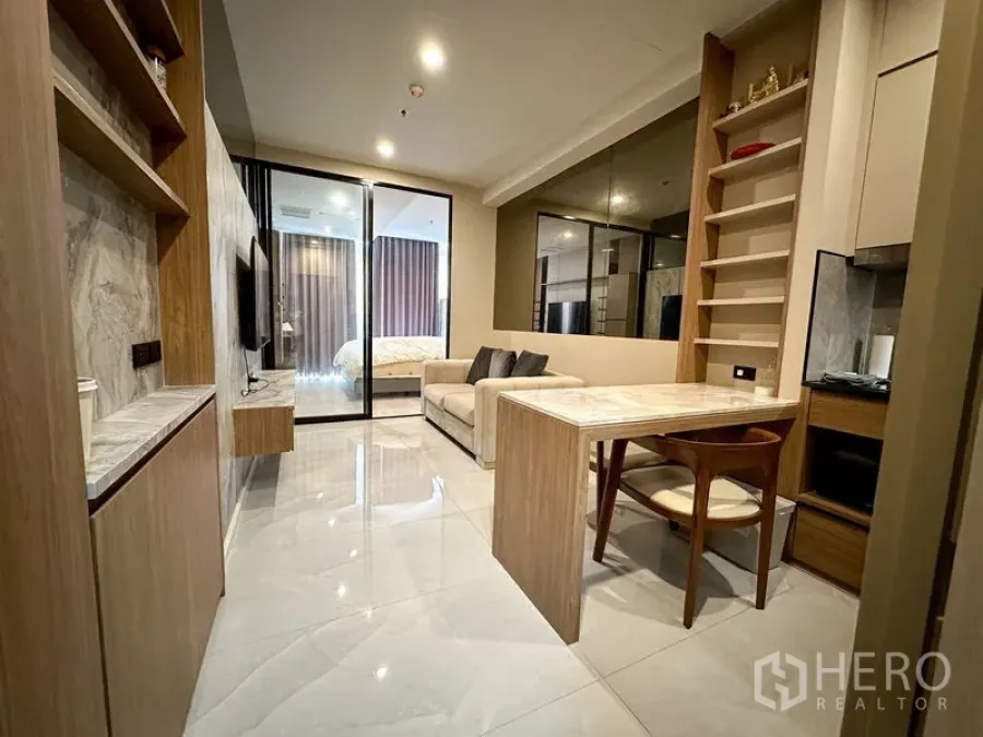 公寓 出租在Pathum Wan, Bangkok - 明亮客厅，通过推拉玻璃面向卧室，瓷砖地面与定制柜体。