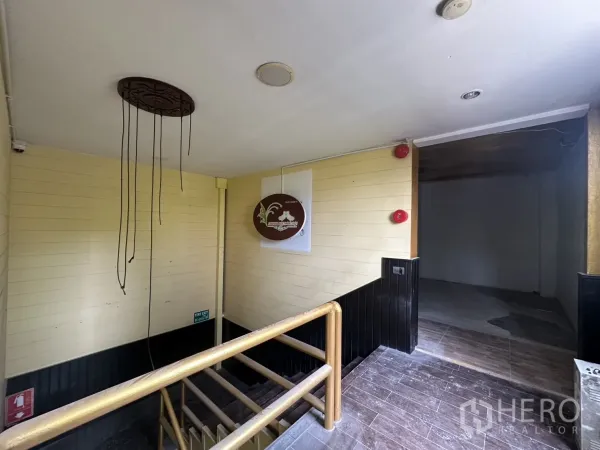 零售空间 出租在Bang Rak, Bangkok - 楼梯平台通往毛坯商铺楼层，带木质扶手与安全装置。