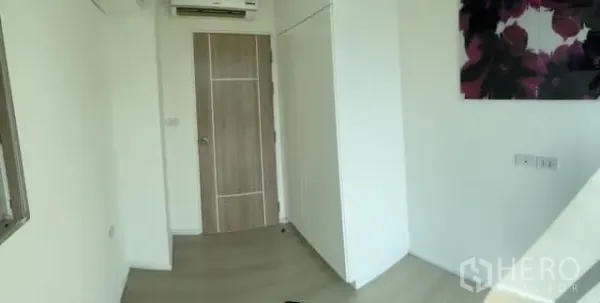 Condominium for sale in Khlong Toei, Bangkok - Second bedroom with wardrobe, air-conditioning and a wood door.