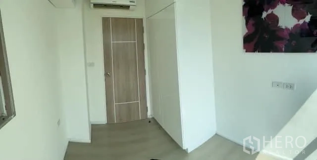 Condominium for sale in Khlong Toei, Bangkok - Second bedroom with wardrobe, air-conditioning and a wood door.