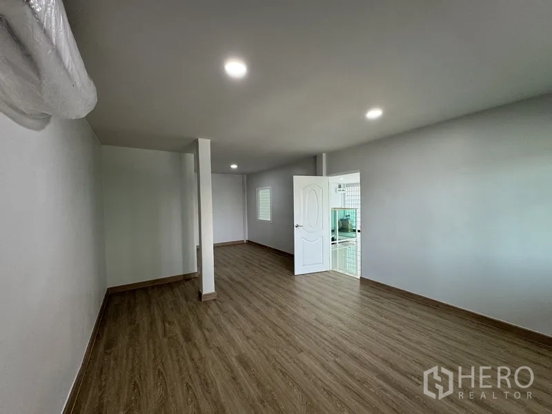 Townhouse for sale in Bueng Kum, Bangkok - Long bedroom with wood floors and recessed lighting, view to ensuite.