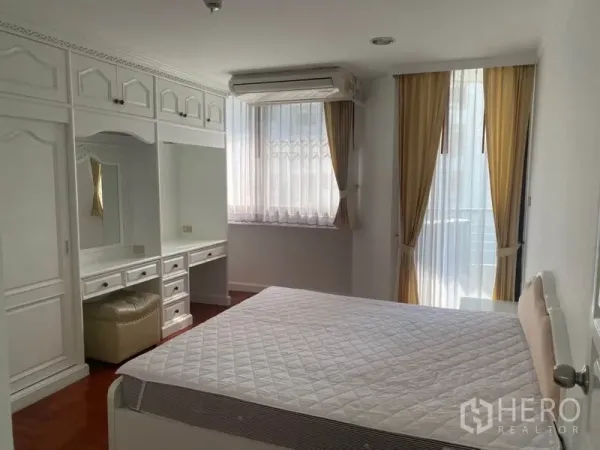 Condominium for rent in Watthana, Bangkok - Bedroom with built-in wardrobes, dressing table and windows with sheer curtains.