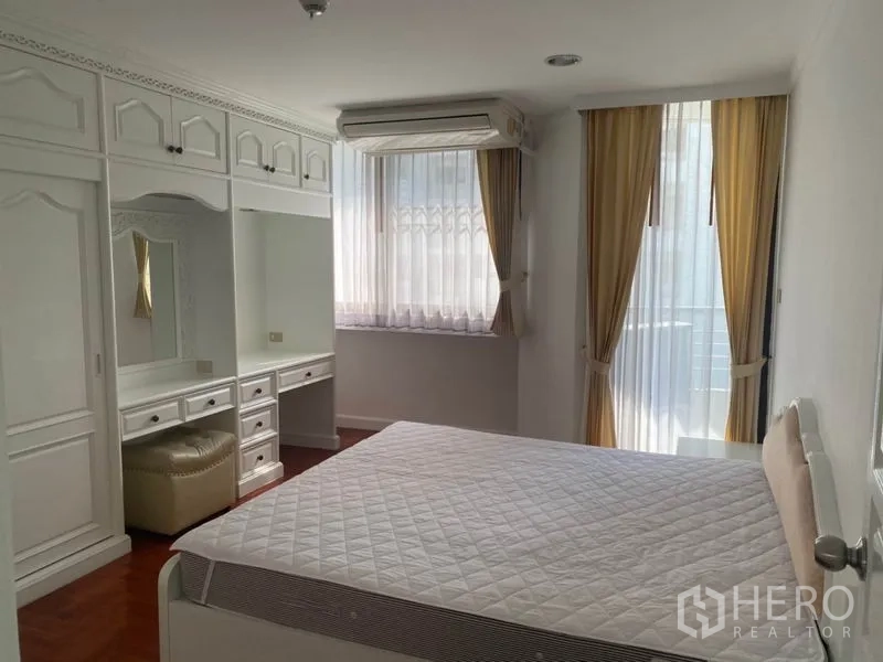 Condominium for rent in Watthana, Bangkok - Bedroom with built-in wardrobes, dressing table and windows with sheer curtains.