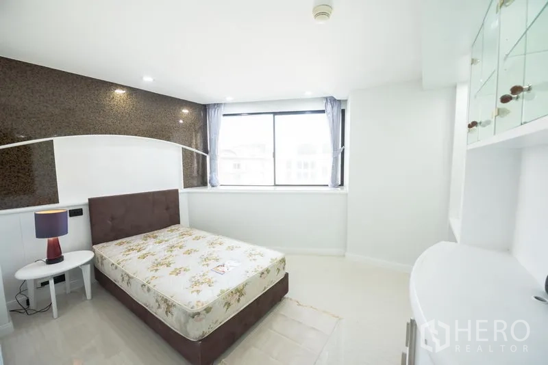 Condominium for rent in Khlong Toei, Bangkok - Bright bedroom with large window, single bed and built-in glass shelving.