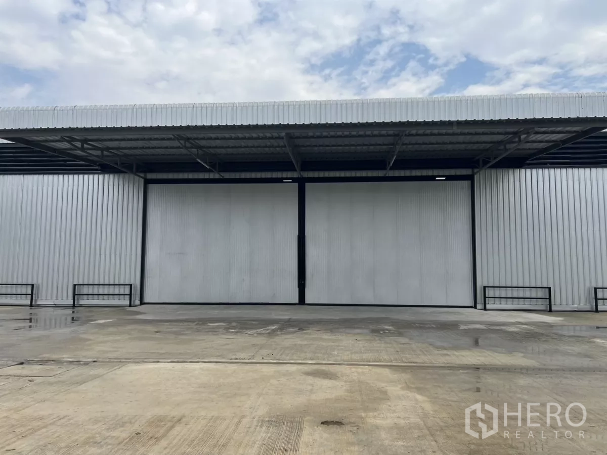 货栈 出租在Lat Lum Kaeo, Pathum Thani - 带雨棚的大型推拉仓库门，前方为宽敞的混凝土作业场地