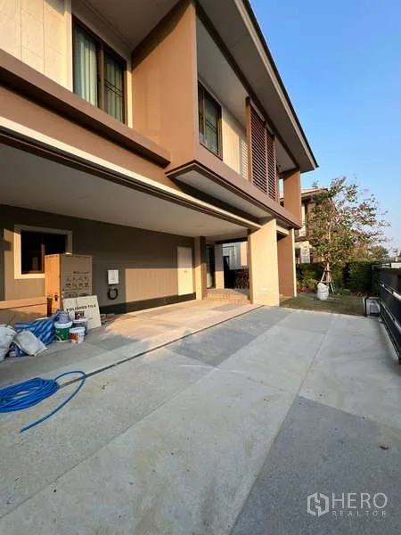 Detached House for rent in Bang Kapi, Bangkok - Side view of driveway and covered parking area beside a small garden.