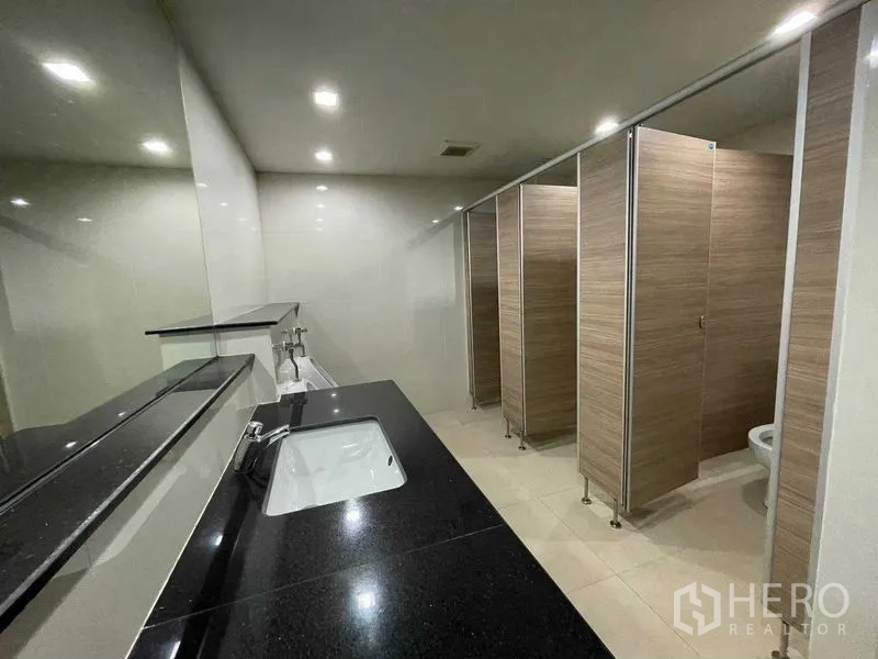 Office Space for rent in Ratchathewi, Bangkok - Modern shared restroom with black granite countertop, mirrors and stalls.
