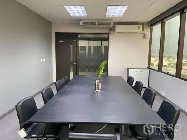 Office Space for rent in Bang Na, Bangkok - Boardroom with long table and black chairs, air-conditioning and a frosted glass door.