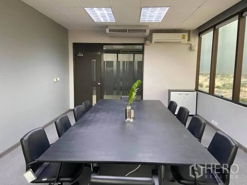 Office Space for rent in Bang Na, Bangkok - Boardroom with long table and black chairs, air-conditioning and a frosted glass door.