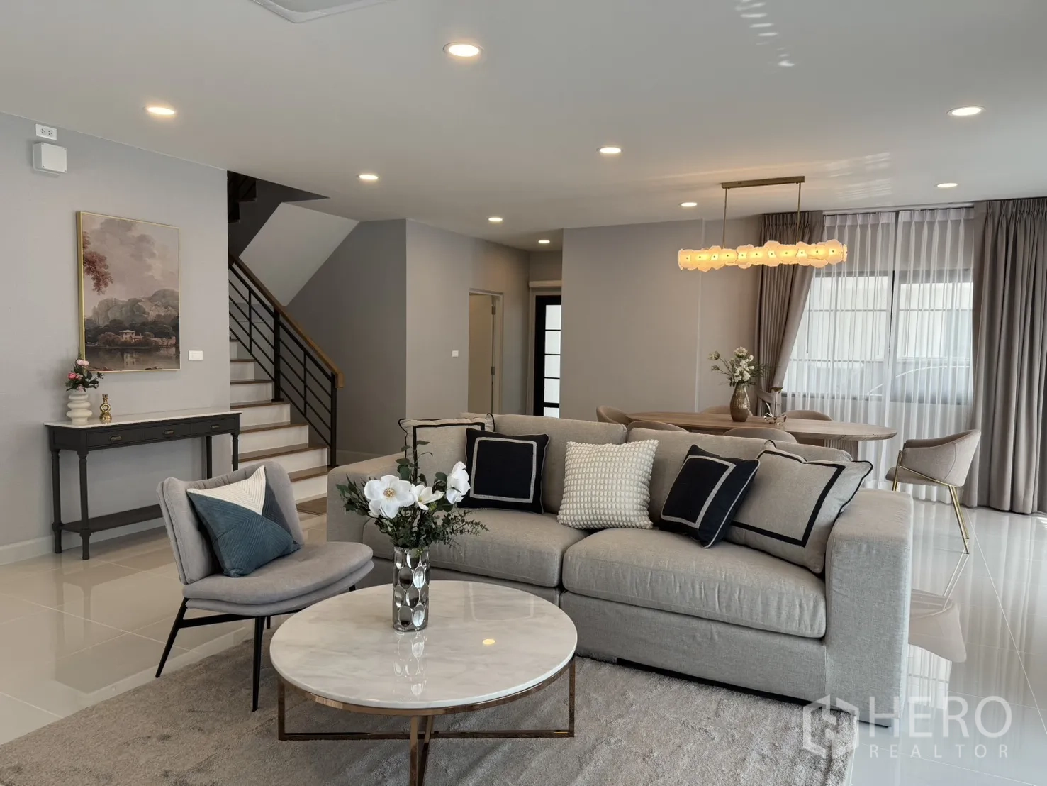 บ้าน for rent in Bang Phli, Samut Prakan - มุมมองเต็มของโซนพักผ่อนและรับประทานอาหารพร้อมบันได โทนสีเทาอ่อนและแสงธรรมชาติ