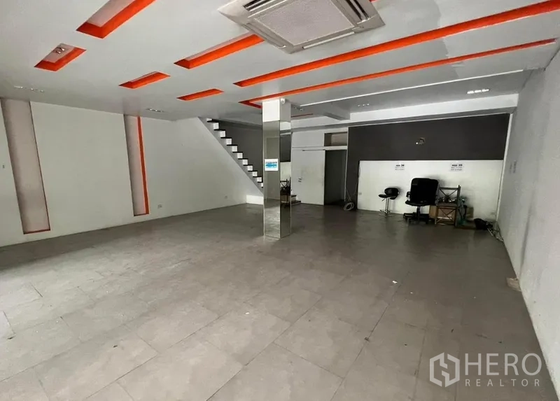 店屋 出租在Watthana, Bangkok - 宽敞零售区，镜面立柱、嵌灯天花、瓷砖地面与楼梯通达。