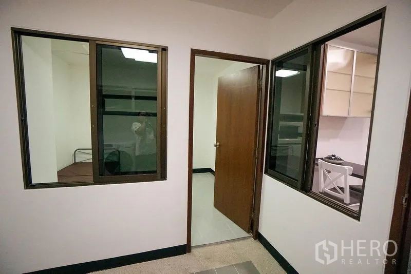 Apartment for rent in Watthana, Bangkok - Utility or maid’s room adjacent to the kitchen with interior windows and a wooden door.