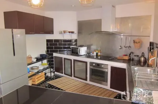 联排别墅 出租在Khlong Toei, Bangkok - 现代厨房，L形台面，黑色地铁砖，配烤箱与不锈钢油烟机。