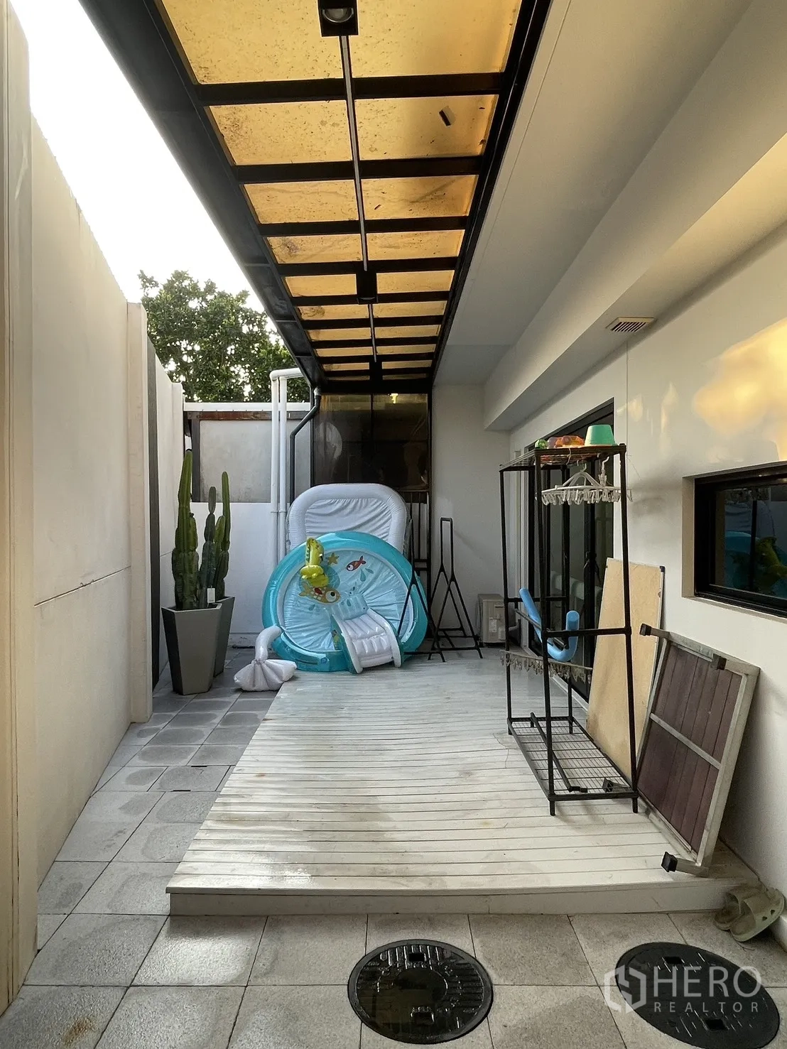 Townhouse for sale in Bang Phli, Samut Prakan - Covered side patio with translucent roof, decked platform, and potted cacti.