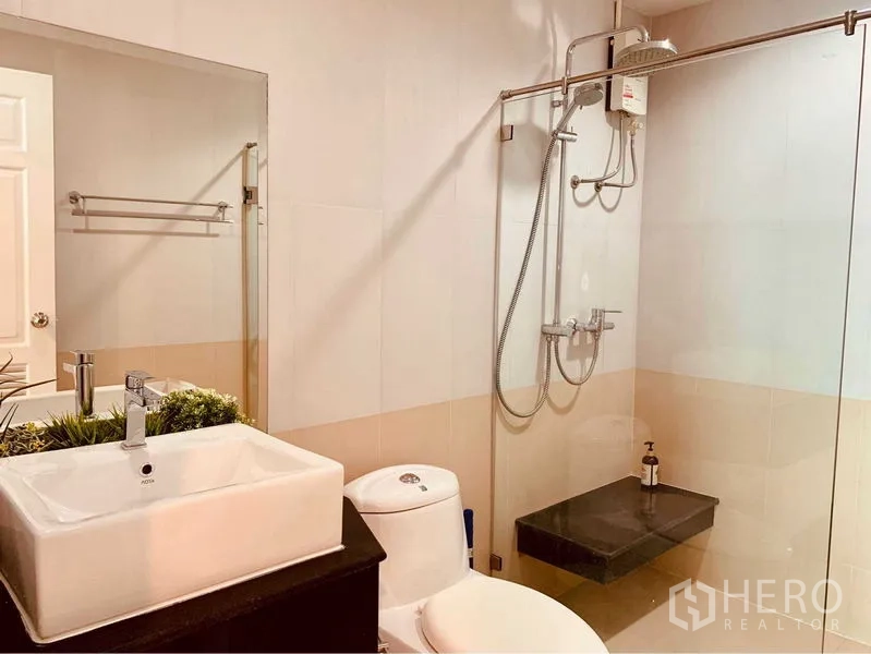 公寓 出租在Watthana, Bangkok - 浴室配玻璃淋浴间、顶喷花洒、方形台盆与坐便器。