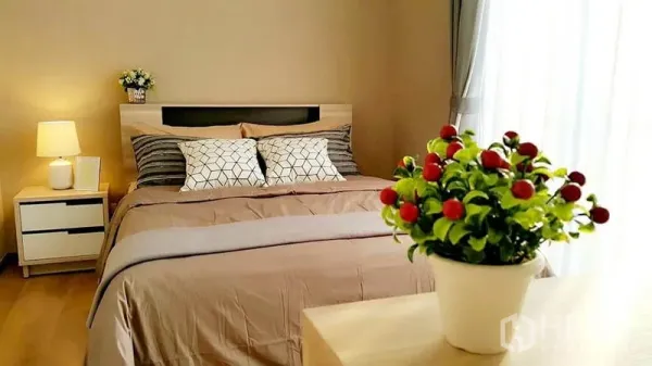 Condominium for rent in Khlong Toei, Bangkok - Sunlit master bedroom with queen bed, bedside tables and sheer curtains.