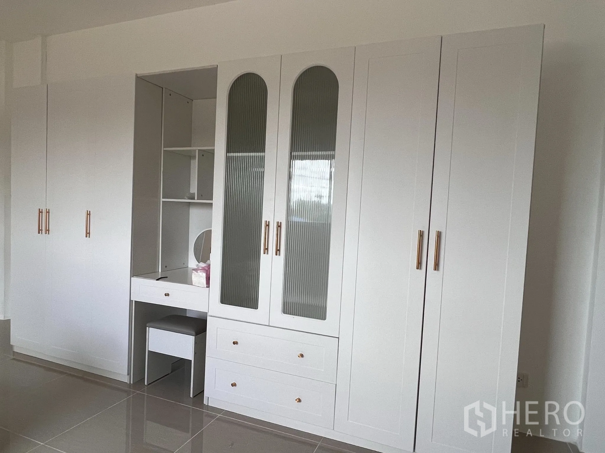 仓库 for sale in Lat Lum Kaeo, Pathum Thani - 明亮房间内的白色定制衣柜，带梳妆台与金色把手。