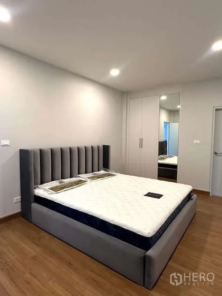 Detached House for rent in Bang Phli, Samut Prakan - Spacious bedroom with upholstered bed and mirrored wardrobe doors.