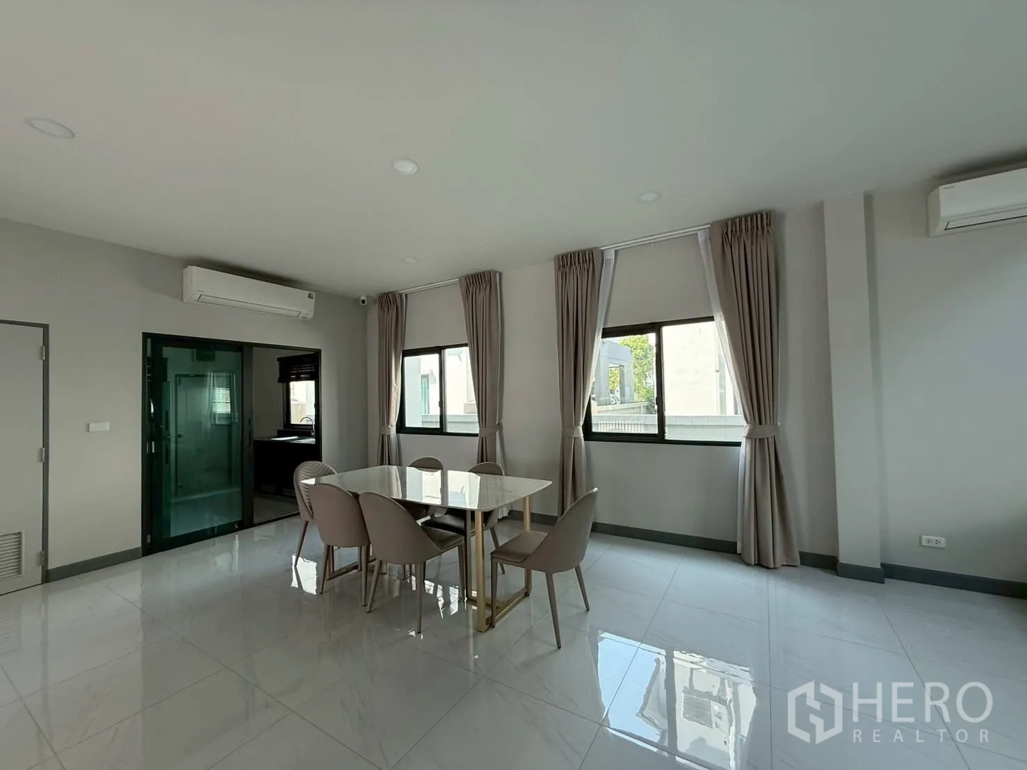 Townhouse for rent - Bright dining area with glossy tile floor, windows with curtains and wall‑mounted air conditioning.